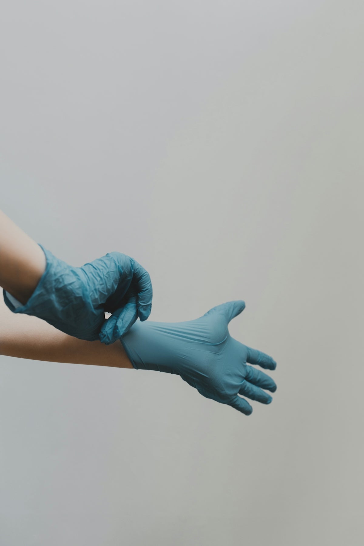 person putting on blue medical gloves